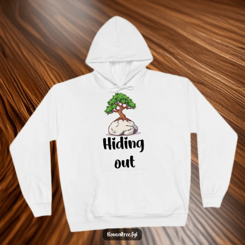 Funny hoodie illustration of a bonsai tree with curious eyes peeking out from behind a small rock, conveying shyness and intrigue.